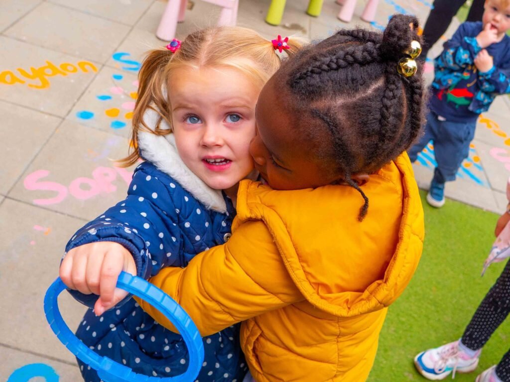 Children sharing a hug and experiencing inclusive practice at Hunny Pot Nursery