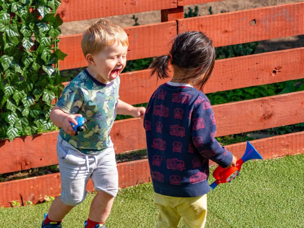 Young children developing social skills together in the nursery garden