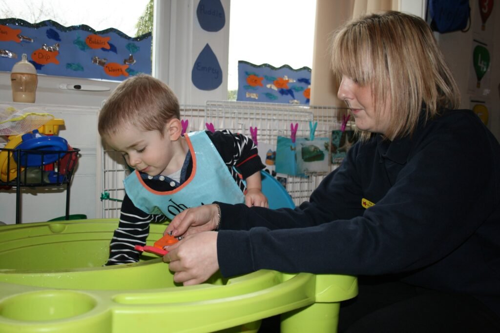 Nursery practitioner supporting a child during an activity at Hunny Pot Nursery