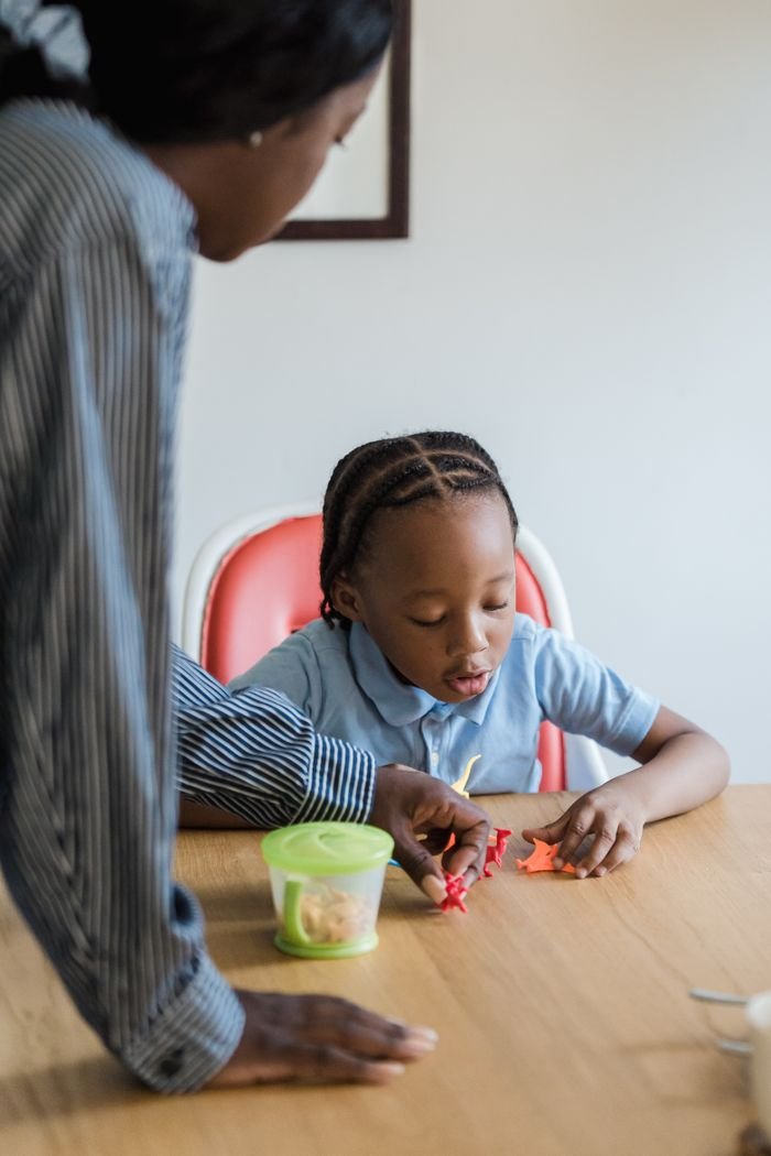 A mother and daughter enjoying playtime with toys at a table indoors.