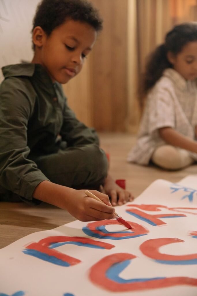Children engaged in a creative painting session on a poster indoors, showcasing artistic expression.